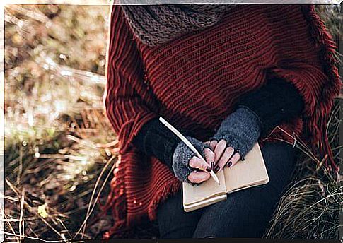 Hands-of-woman-writing-on-a-notebook-in-a-field